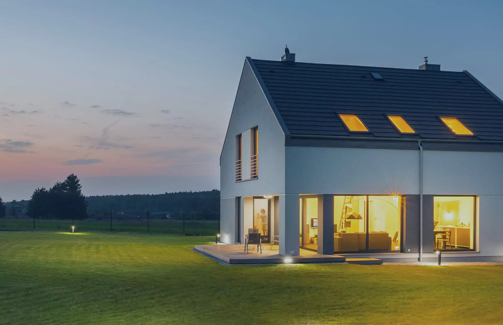 Modern two-storey home at dusk with warm interior lighting